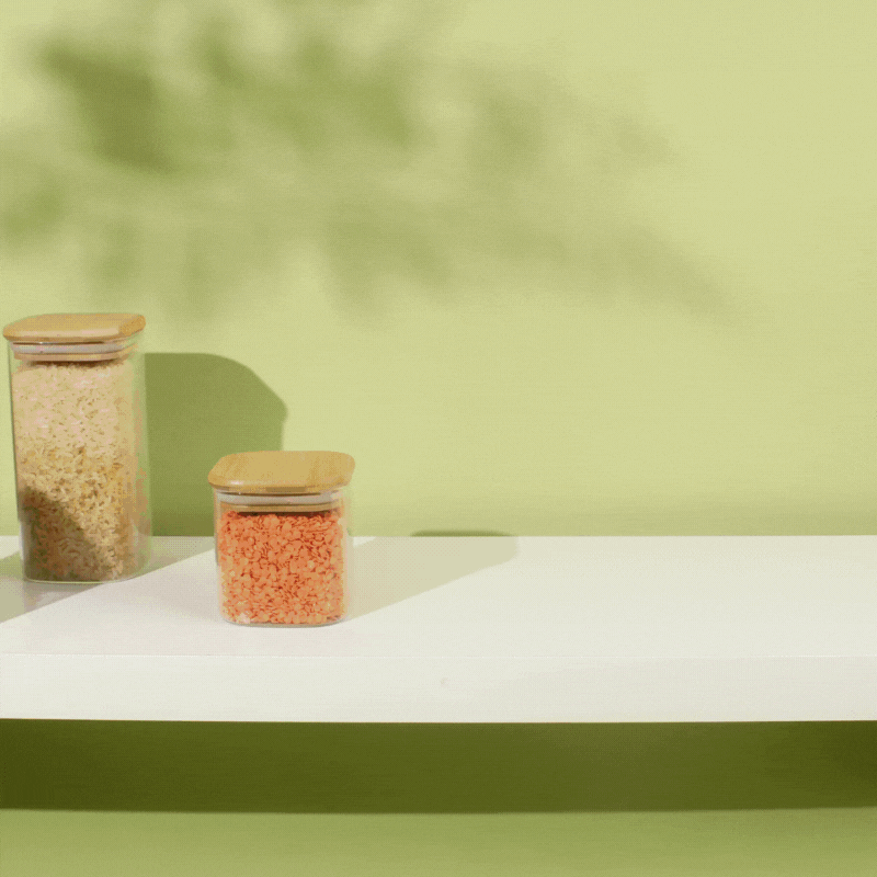 A GIF of set of storage tins with a Cherry print sliding across a shelf, filled with kitchen utensils