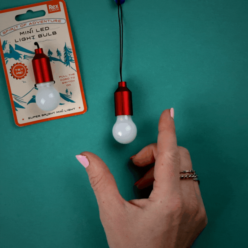 A hand pulls on a keyring which has a little lightbulb shaped light, turning it on and off
