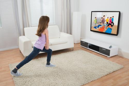Girl Doing Exercise While Watching Program On Television