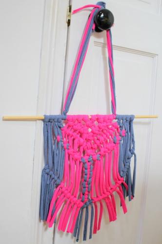 Pink and blue macrame decoration hanging on a doorknob