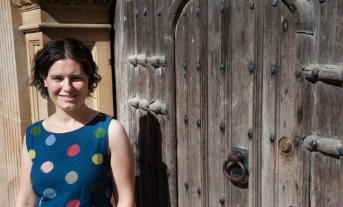 photograph of Lucy standing in front of a regal wooden door