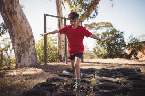 Tire them out with an obstacle course Boy running over tyres in obstacle course