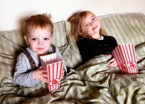 two-children-sitting-in-bed-with-popcorn