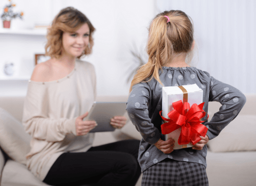 Daughter holding surprise gift behind her back for mum