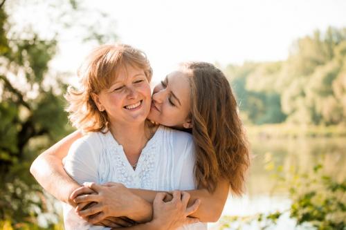 Teenage daughter hugging mum from behind