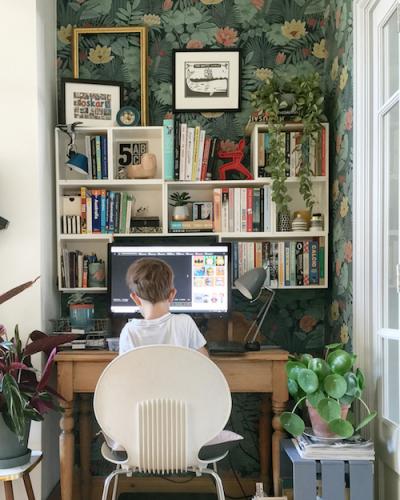 small boy sitting at desk with books surrounding the workspace