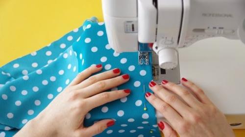 hands-with-fabric-and-sewing-machine