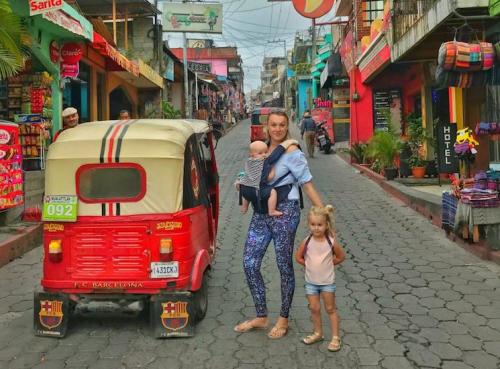 mother with two children standing next to a tuk tuk