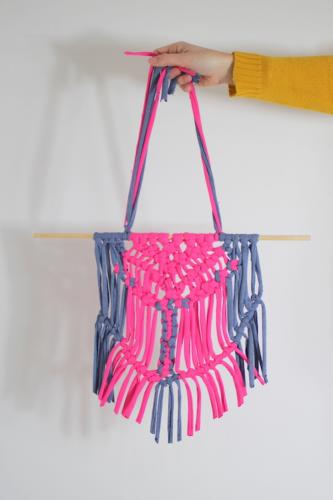 Female hand holding a pink and blue macrame decoration