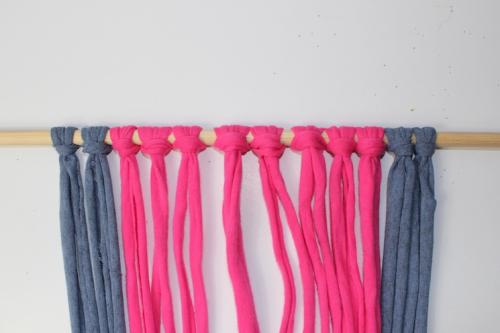 a row of luggage knots tied onto a wooden dowel for a macrame decoration