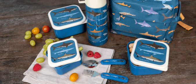 A group shot of Sharks products on a table, including a backpack, a flask, some snack boxes and some children's cutlery