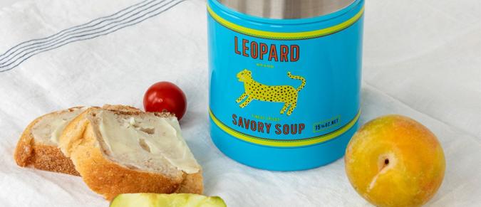 Leopard design steel food flask next to some bread and fruit