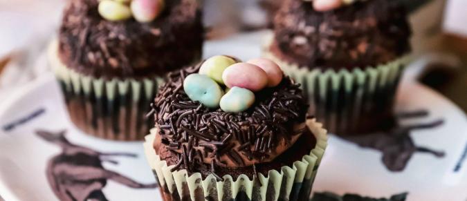 Chocolate cupcakes with mini eggs on top, on a dinosaur plate