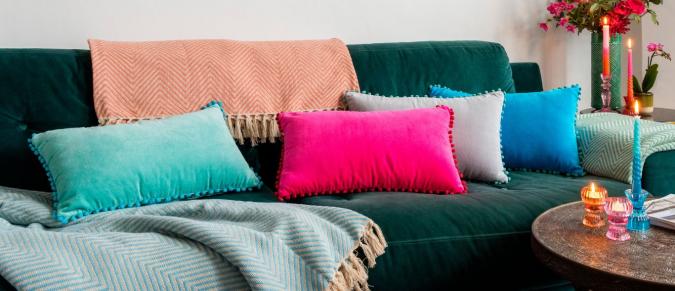 Bright cushions and throws on a dark green sofa