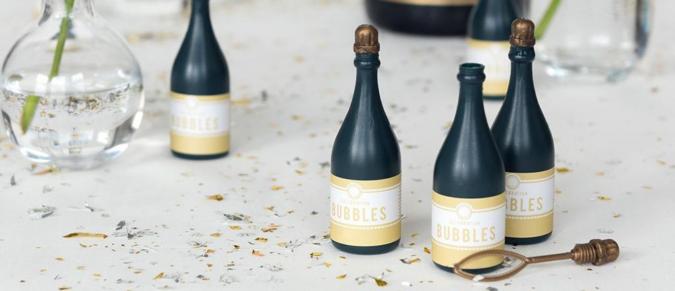 Celebration bottle bubbles on a table in front of a bottle of champagne