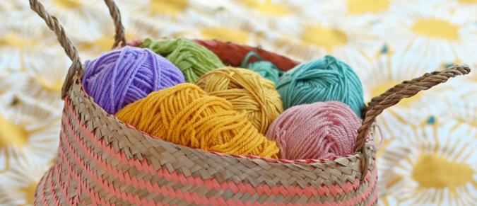 A coral belly basket holding colourful balls of yarn