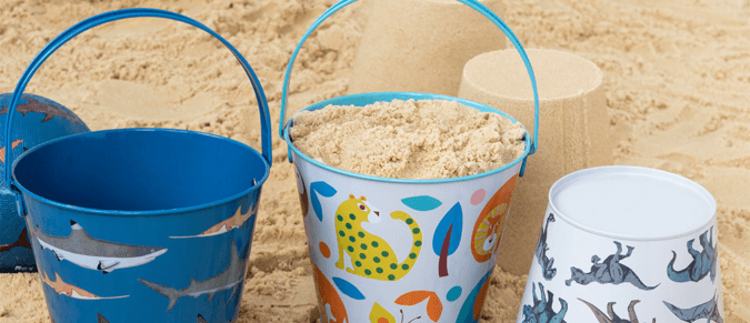 Three tins buckets on a beach, filled with sand