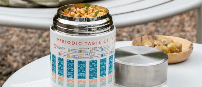 An open food flask with a Periodic Table design sits on a table