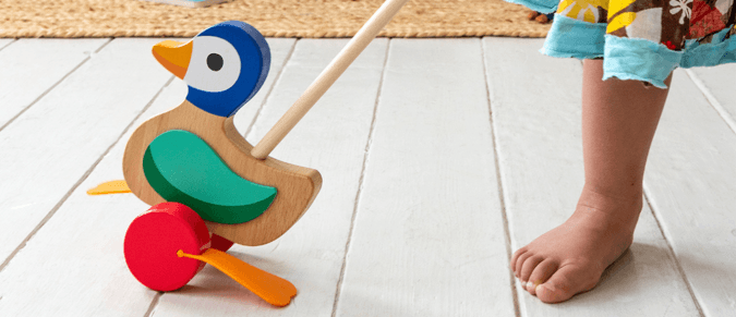 A wooden duck on a stick with flappy rubber feet