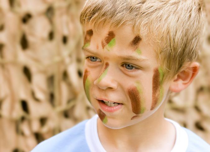 Pair them up to apply each other’s war paint Young boy with army facepaint
