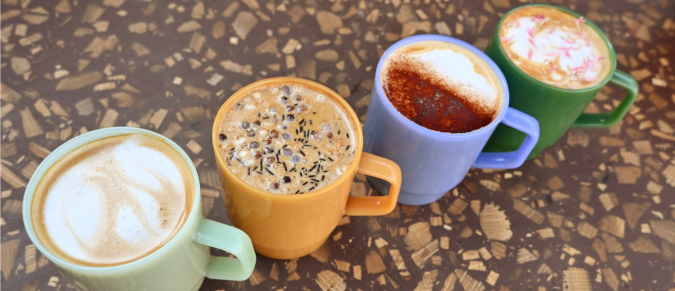 Four coffee cups each with decorations or latte art on top