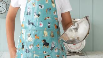 Colourful aprons designed for children, each featuring playful dog illustrations.