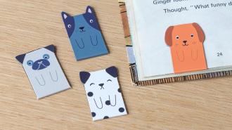 Four magnetic dog bookmarks, one of which is in the corner of a book