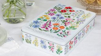 Wild Flowers biscuit tin on a table next to some cupcakes and a vase of flowers