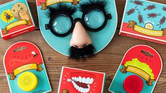 A selection of novelty toys including joke glasses with a nose and moustache, fake teeth, and other small trinkets, laid out on a wooden surface.