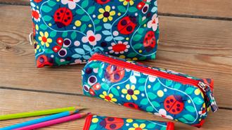 Floral and Ladybird-patterned pencil cases and matching stationery items displayed on a wooden surface—ideal for school or home use.
