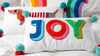 Embroidered cushion with pom poms