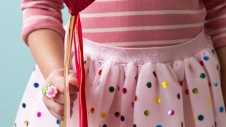 Kid holding a red heart wand with glittery top and ribbon streamers 