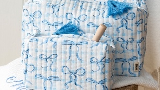 Two matching quilted fabric wash bags with a blue bow print