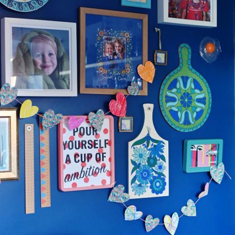 Homemade paper heart garland draped across pictures on a gallery wall