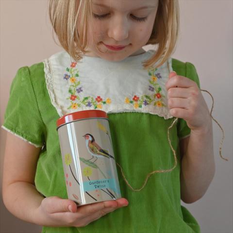 A child holds a tin of gardening twine
