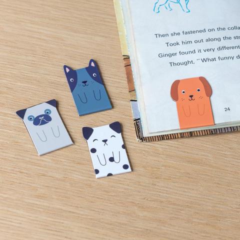 Four magnetic dog bookmarks, one of which is in the corner of a book