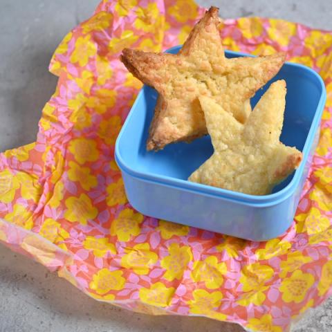 Star-shaped biscuits in a blue lunchbox on brightly coloured greaseproof paper