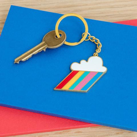 Cloud burst keyring attached to a gold key, resting on a blue notebook