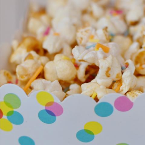 A paper tub of popcorn with colourful sprinkles 