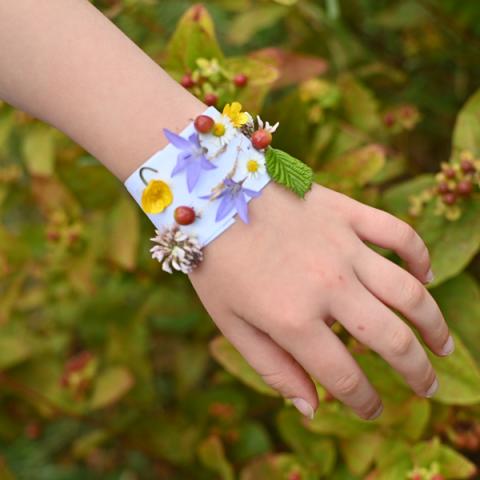 Pretty flowers are stuck to a piece of paper wrapped around a child's wrist