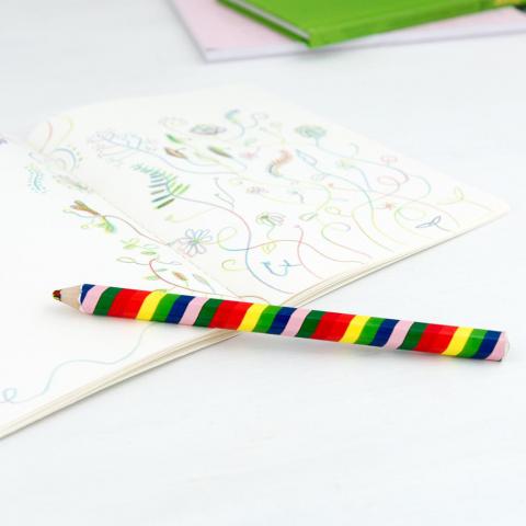 Rainbow pencil on an open notebook filled with doodles