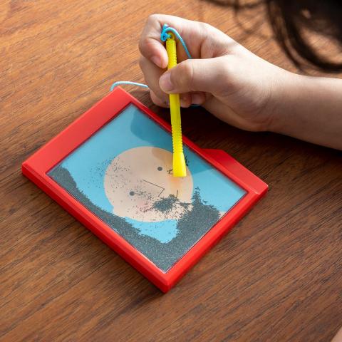 A child plays with a fuzzy face magnet game on a table