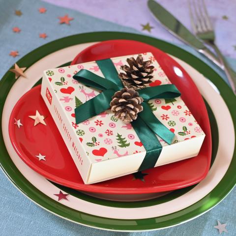 Box of Christmas matches wrapped in a ribbon on a red plate