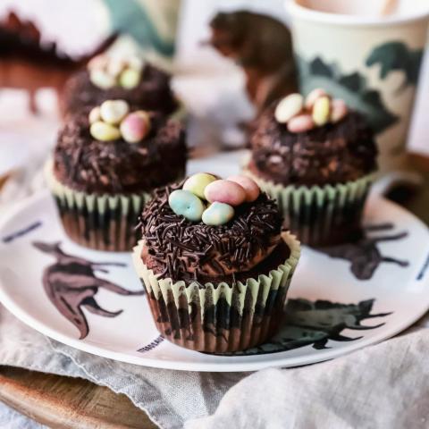Chocolate cupcakes with mini eggs on top, on a dinosaur plate