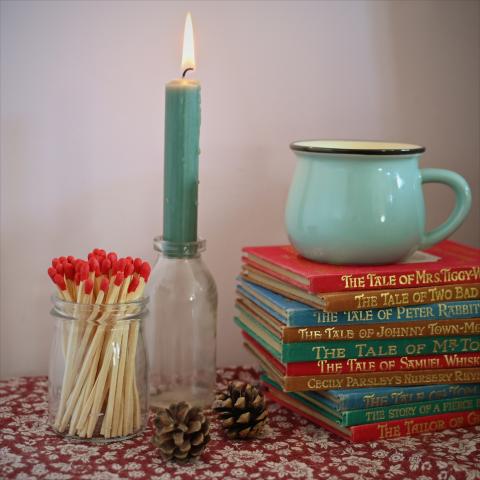 Red tipped matches in a jar next to a candle