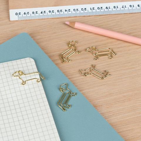 Dog-shaped paper clips on a table next to a notebook, ruler and pencil