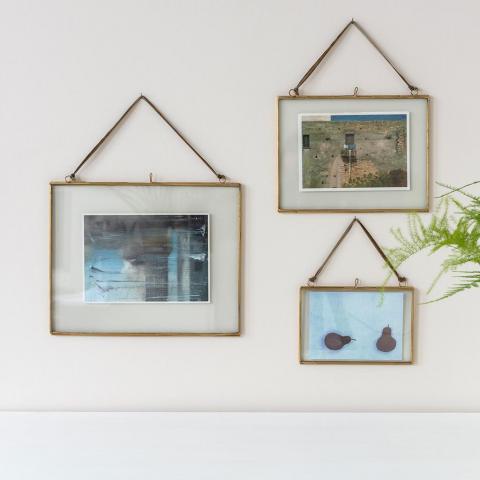 Three landscape brass frames on a wall