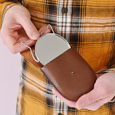 A man holds a travel shaving mirror