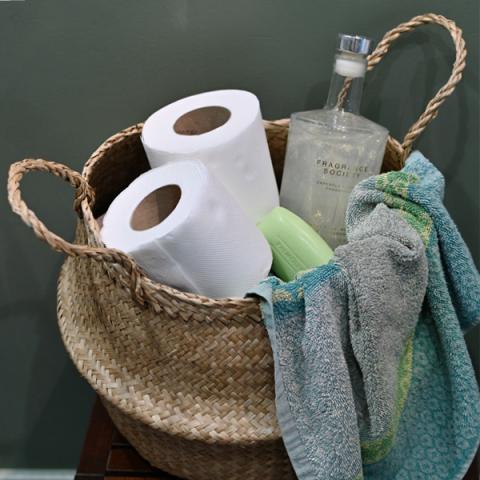 A neutral belly basket filled with toilet rolls and a towel