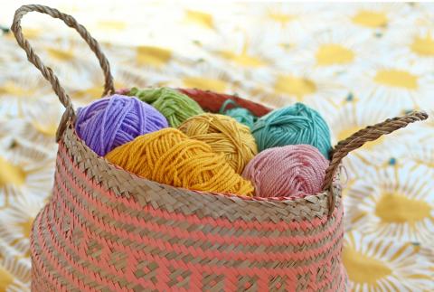 A coral belly basket holding colourful balls of yarn